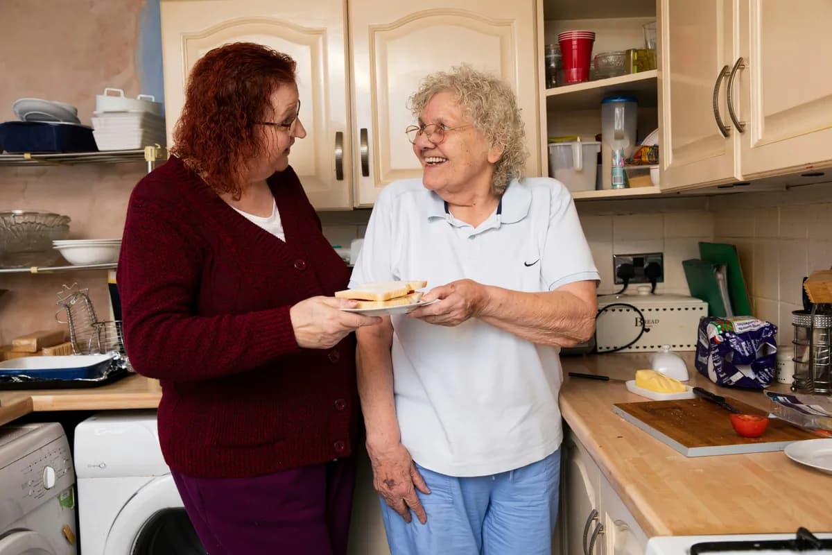 two women discussing, laughing in the kitchen of a care home