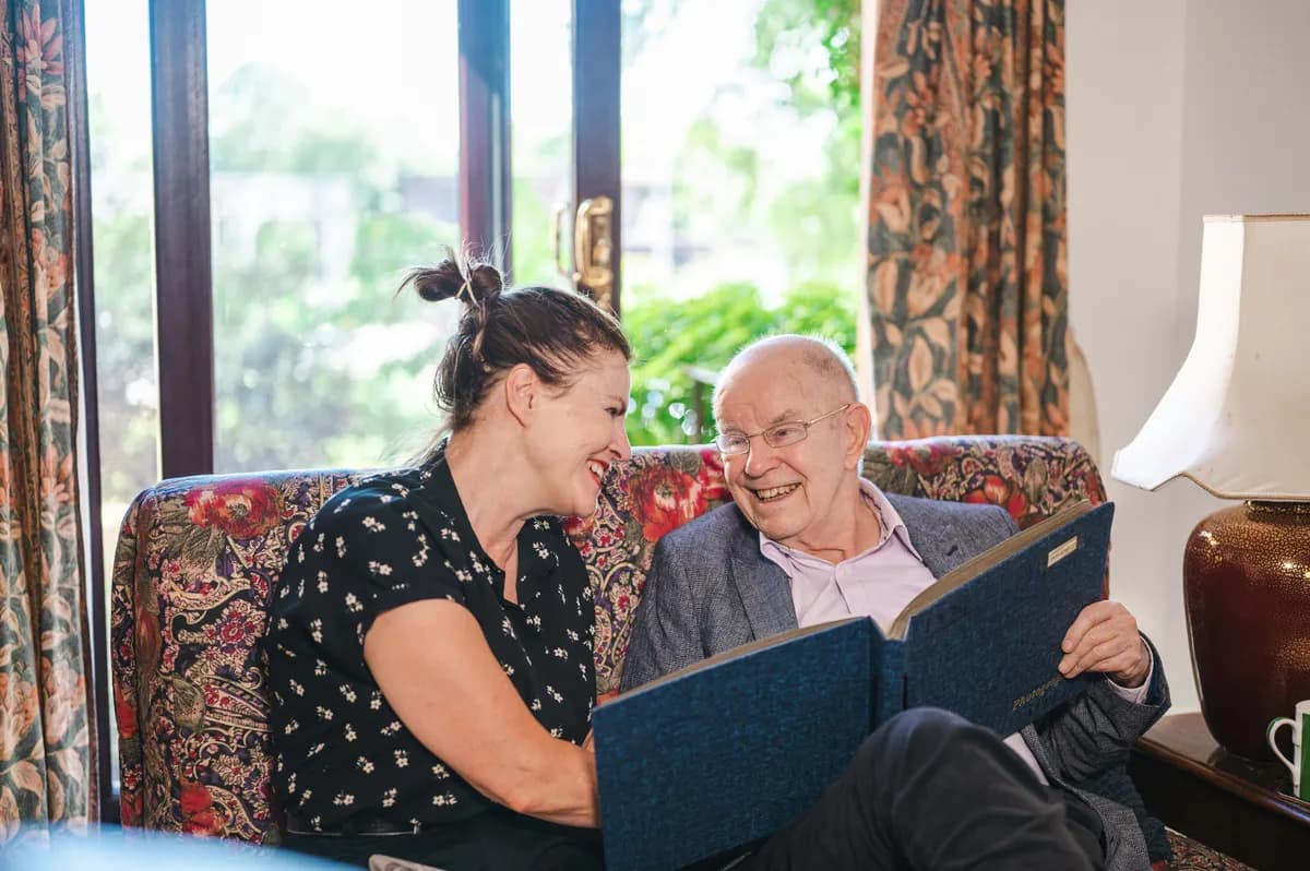 A care home staff reading and smiling with a care patient
