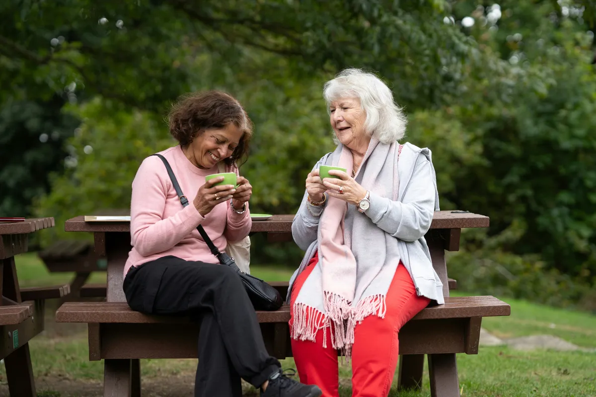 two ladies having coffee and laughing together